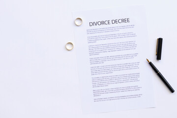 Two broken golden wedding rings divorce decree document. Divorce and separation concept. Top view.	