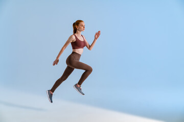 Fototapeta na wymiar Photo of athletic focused sportswoman running while working out