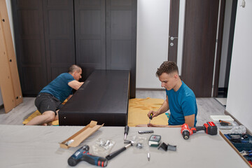 Father and son assembling furniture in new home