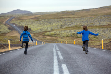 Obraz premium Kids running on an empty road in beautiful nature in Snaefellsjokull National Park in Iceland, autumntime