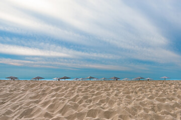 Umbrellas from the sun and the sea. Dune of white sand in the foreground.