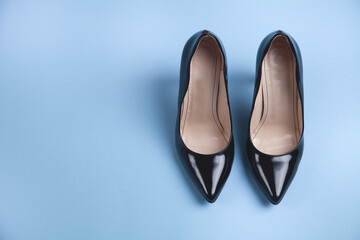 Black high heeled shoes on blue background. Feminine stylish shoes.