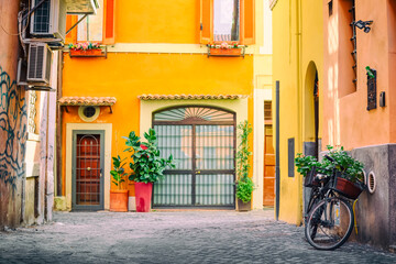 Fototapeta na wymiar Old cozy street in Trastevere, Rome, Italy with a bicycle and yellow house.