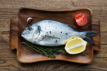 Raw fish cooking and ingredients. Dorado, lemon, herbs and spices. Top view on stone table