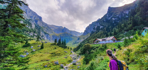 Wanderin vor Berghütte in einem Tal der rumänischen Karpaten