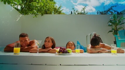 Portrait of diverse multiracial attractive people in swimwear leanning on folded hands at poolside, drinking juice and cocktail while joyful friends having pool party and celebrating summer vacations.
