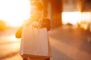 Hand of young man with paper bags with purchases. Handsome man  holds out shopping bags....