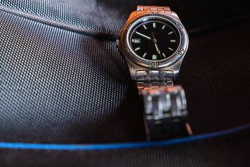 A stainless steel watch on a black background