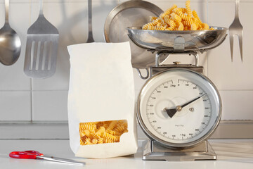 pack of fusilli pasta and raw fusilli on a kitchen scale with copy space for your text