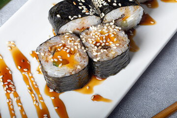 Sushi Sets Nigiri, Uramaki, California, Philadelphia, on a white plate. Nearby ginger and wasabi. Soy sauce in a white bowl. On a light gray background.