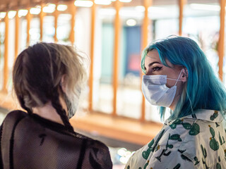 Mujeres jóvenes con mascarilla en un centro comercial respetando las medidas de seguridad y...