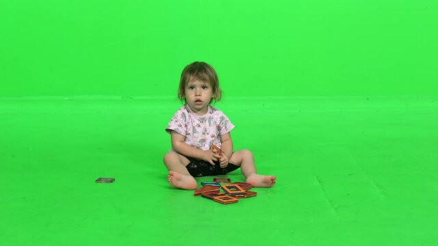 Cute toddler girl playing with magnets game over green screen.