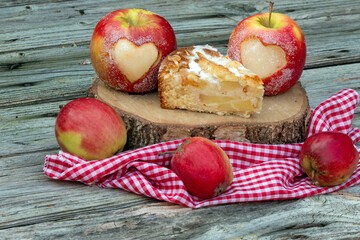 Äpfel mit Herz und Apfelkuchen rustikal auif Holz