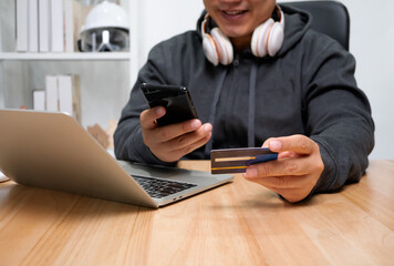 A Man holding credit card and using a smartphone for payment online for purchase after order products via the internet. The concept of technology for e-commerce (electronic commerce)