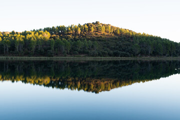 Reflection of calm water, trees and mountains at sunset in the lake of the natural park of 'Lagunas...