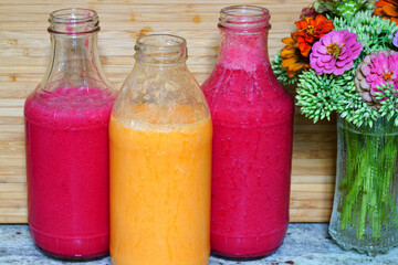 Fototapeta na wymiar Glass bottles filled with colorful fresh homemade beet and peach smoothies