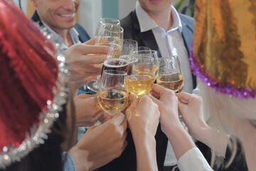 Close up business people's hands enjoy clinking wine glasses for celebration or congratulation together at the office party. 