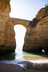Sandy beach with an arched bridge surrounded by cliffs called 'Praia dos Estudantes'. Lagos, Algarve, Portugal.