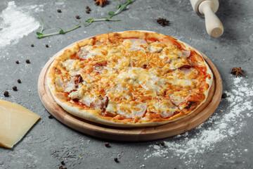 pizza with cheese, sauce and ham, bacon, salami on a gray dark background