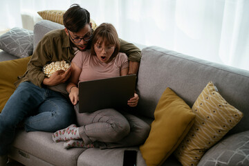 Young couple watching movie on lap top. Loving couple enjoying at home.