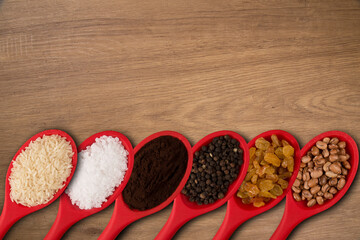 red spoons with grains and spices, on a wooden background.top wiew.