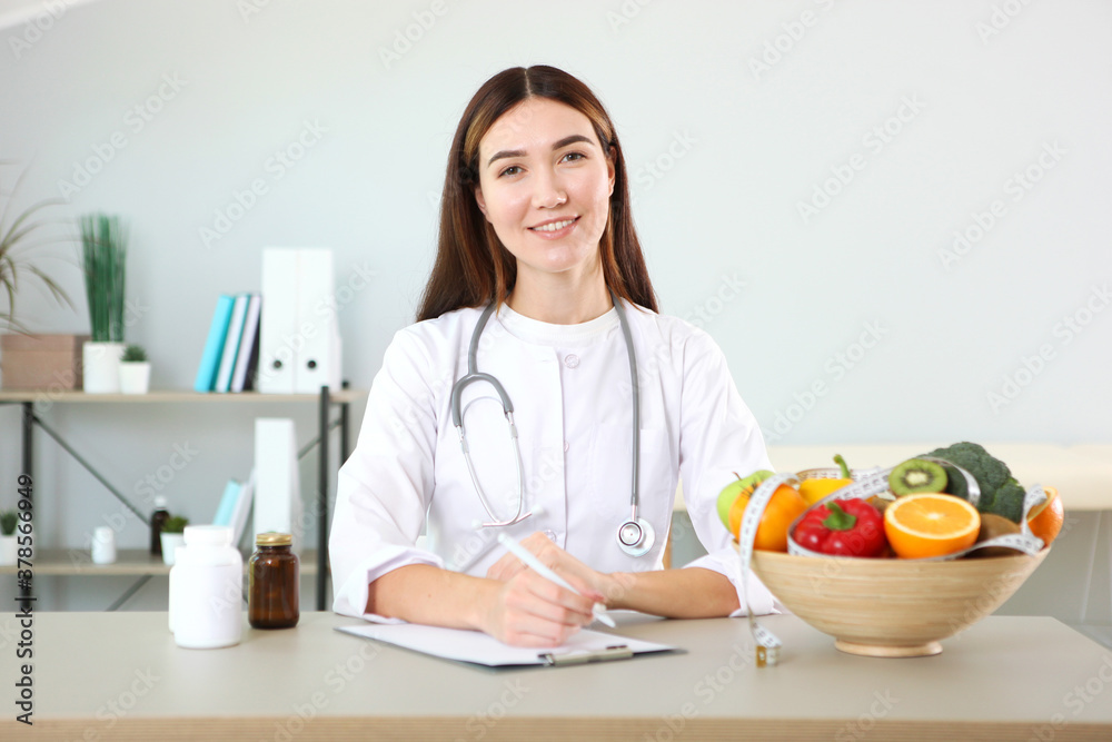 Wall mural young doctor nutritionist in his office demonstrates the concept of healthy eating. help with weight