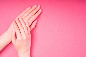Beautiful female hands showing fresh cute manicure, skin and nail care concept, pink background copy space