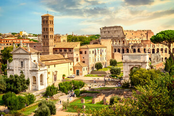 Fototapeta premium The Colosseum and Arch of Constantine in Rome, Italy during summer sunny day sunset. The world famous colosseum landmark in Rome.