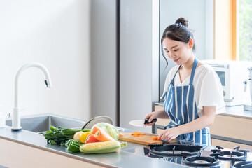 キッチンで料理する若い女性