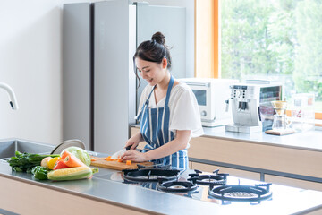 キッチンで料理する若い女性