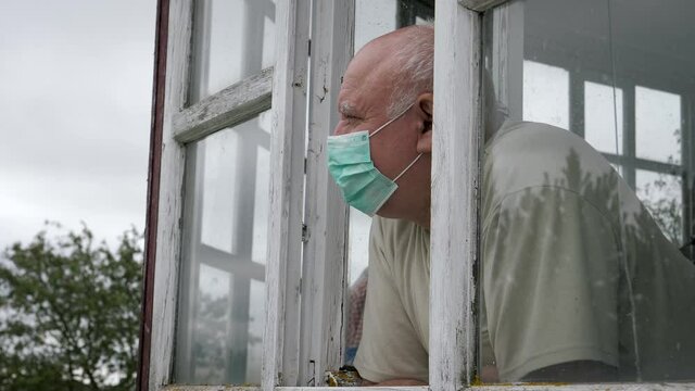 Portrait Of Old Caucasian Man In Safety Medical Mask Looking Out Of Window