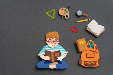 Thoughtful schoolboy sitting with textbook. Stationery supplies such as schoolbag, notebook,...