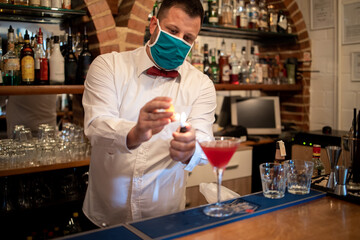 A young waiter, making a cocktail of alcohol in the restaurant's sleigh