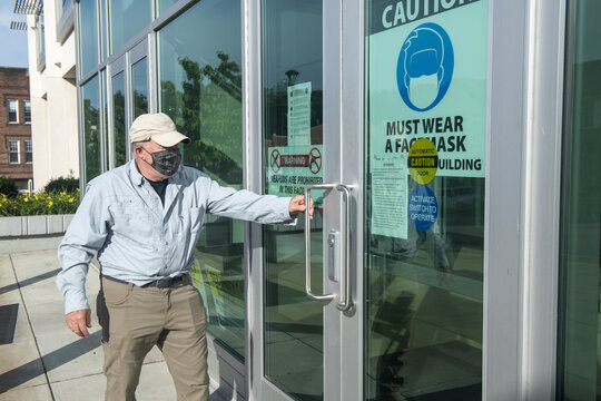 Man Opening Door With Must Wear Mask Sign