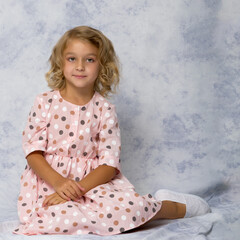 Fototapeta premium Little girl is sitting on the floor.The concept of a happy childhood.