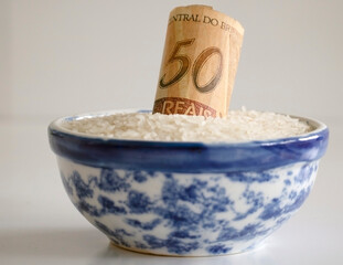 Expensive rice in Brazil due economic pandemic crisis. R$50 real paper bill inside raw rice grains bowl. Concept of rising rice prices in the Brazilian basic basket, return of inflation.