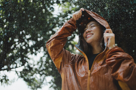Asian woman is outdoors while it's raining. She felt refreshed.