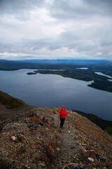 Fototapeta premium Adventurous Girl Hiking up a steep rocky mountain during a dark morning sunrise. Taken on a hike to Kings Throne Peak in Kluane National Park, Yukon, Canada.