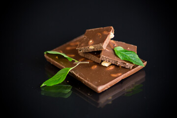 sweet dark chocolate with nuts on black background