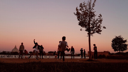 Children play ball in the park of Monte Ciocci in Rome, in the background a panoramic view of Rome and a view of the dome of St. Peter's at sunset.