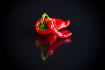 two hot spicy cayenne peppers on black background