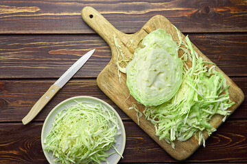 Shredded fresh cabbage salad flat lay on wooden kitchen table background.
