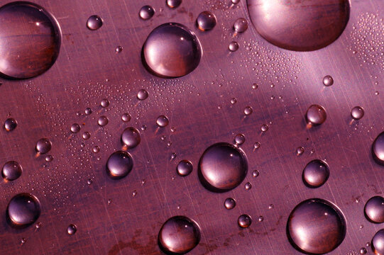 Surface tension. Water drops on the surface covered with foil.