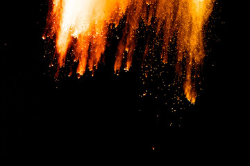 Abstract orange powder explosion. Closeup of orange dust particle splash isolated on black background.