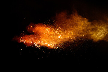 Fototapeta na wymiar Abstract orange powder explosion. Closeup of orange dust particle splash isolated on black background.