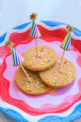 Rainbow sprinkle Cookies on a festive party plate with colorful cake toppers for birthday celebration