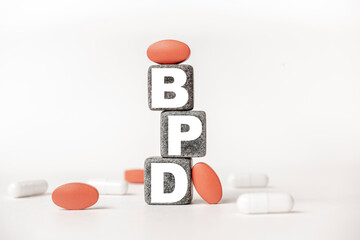 a group of white and red pills and cubes with the word BPD: Borderline personality disorder on them, white background. Concept carehealth, treatment, therapy.
