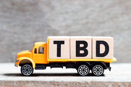Truck hold letter block in word TBD (Abbreviation of to be defined, discussed, determined, decided, deleted or declared) on wood background