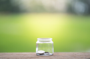 Money saving, Hand putting coin in glass jar with coins inside For now and future 