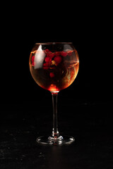 Alcoholic cocktail with cranberries and berry syrup in a transparent glass on a dark background